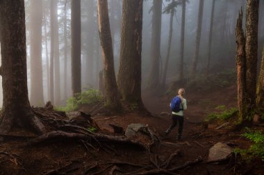Maceracı bir kız sisli ve yağmurlu bir gün boyunca ormanda bir iz üzerinde yürüyüş. Alınan Cypress Provincial Park, Vancouver, British Columbia, Kanada.