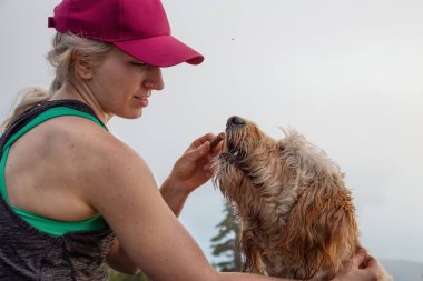 Maceracı Kız güneşli ve bulutlu bir yaz gününde Gereksiz Dağ tepesinde bir köpek ile yürüyüş olduğunu. Batı Vancouver, British Columbia, Kanada'da bulunan.