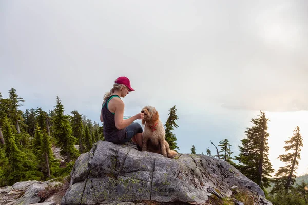 Adventurous Girl is hiking with a dog on top of Unnecessary Mountain during a sunny and cloudy summer day. Located in West Vancouver, British Columbia, Canada.