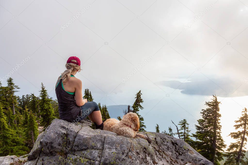 Adventurous Girl is hiking with a dog on top of Unnecessary Mountain during a sunny and cloudy summer day. Located in West Vancouver, British Columbia, Canada.