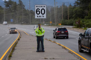 Squamish, British Columbia, Kanada - 26 Temmuz 2019: Fake Cardboard Cutout Polis Memuru şehre müdahale etmeden önce Sea to Sky Highway'de hız tabancası tutuyor.