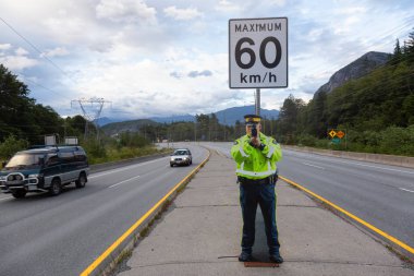 Squamish, British Columbia, Kanada - 26 Temmuz 2019: Fake Cardboard Cutout Polis Memuru şehre müdahale etmeden önce Sea to Sky Highway'de hız tabancası tutuyor.