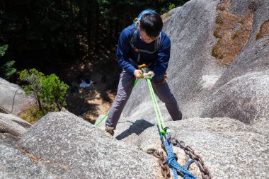 Rock Climber güneşli bir yaz günü boyunca sarp bir uçurumdan aşağı Rappeling olduğunu. Squamish, British Columbia, Kanada'da çekildi.
