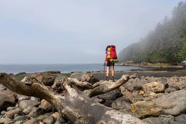 Adventurous girl hiking Juan de Fuca Trail to Bear Beach on the Pacific Ocean Coast during a sunny and foggy summer morning. Taken near Port Renfrew, Vancouver Island, BC, Canada.