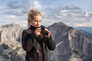 Canmore, Alberta, Kanada - 13 Ağustos 2019: Macera kadın Fotoğrafçı bulutlu bir gün boyunca kayalık bir dağın tepesinde fotoğraf çekiyor.