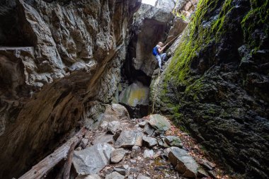 Skaha Bluffs Provincial Park, Penticton, British Columbia, Kanada - 11 Ağustos 2019: Maceracı kız kayalık bir mağaraya tırmanıyor.