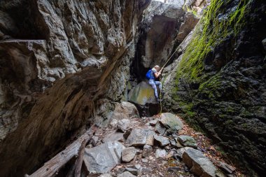 Skaha Bluffs Provincial Park, Penticton, British Columbia, Kanada - 11 Ağustos 2019: Maceracı kız kayalık bir mağaraya tırmanıyor.