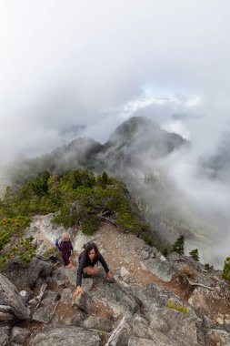 Maceracı Kız bulutlu bir yaz sabahı boyunca güzel bir kayalık dağ kadar dik bir iz kadar yürüyüş olduğunu. Crown Mountain'da çekilmiş, Kuzey Vancouver, Bc, Kanada.