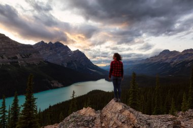 Maceracı kız canlı bir yaz gün batımı sırasında güzel Kanada Rockies ve Peyto Gölü bakan bir uçurumun kenarında duruyor. Alınan Banff Ulusal Parkı, Alberta, Kanada.
