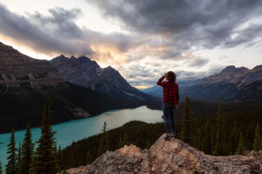Maceracı kız canlı bir yaz gün batımı sırasında güzel Kanada Rockies ve Peyto Gölü bakan bir uçurumun kenarında duruyor. Alınan Banff Ulusal Parkı, Alberta, Kanada.