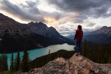 Maceracı kız canlı bir yaz gün batımı sırasında güzel Kanada Rockies ve Peyto Gölü bakan bir uçurumun kenarında duruyor. Alınan Banff Ulusal Parkı, Alberta, Kanada.