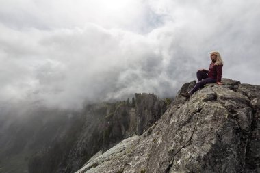 Bulutlu bir yaz sabahı engebeli kayalık dağın tepesinde Maceracı Kız. Crown Mountain'da çekilmiş, Kuzey Vancouver, Bc, Kanada.