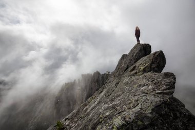 Bulutlu bir yaz sabahı engebeli kayalık dağın tepesinde Maceracı Kız. Crown Mountain'da çekilmiş, Kuzey Vancouver, Bc, Kanada.