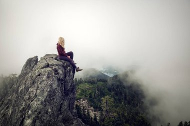 Bulutlu bir yaz sabahı engebeli kayalık dağın tepesinde Maceracı Kız. Crown Mountain'da çekilmiş, Kuzey Vancouver, Bc, Kanada.