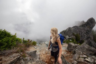 Maceracı Kız bulutlu bir yaz sabahı boyunca güzel bir kayalık dağ kadar dik bir iz kadar yürüyüş olduğunu. Crown Mountain'da çekilmiş, Kuzey Vancouver, Bc, Kanada.
