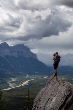 Maceracı Kız bulutlu ve yağmurlu bir gün boyunca kayalık bir dağın tepesinde fotoğraf çekmek. Lady Macdonald, Canmore, Alberta, Kanada'dan alındı.