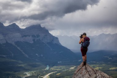 Maceracı Kız bulutlu ve yağmurlu bir gün boyunca kayalık bir dağın tepesinde fotoğraf çekmek. Lady Macdonald, Canmore, Alberta, Kanada'dan alındı.
