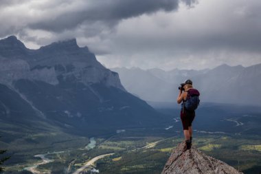 Maceracı Kız bulutlu ve yağmurlu bir gün boyunca kayalık bir dağın tepesinde fotoğraf çekmek. Lady Macdonald, Canmore, Alberta, Kanada'dan alındı.