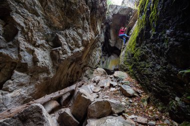 Maceracı kız kayalık bir mağaraya iniyor. Skaha Bluffs İl Parkı, Penticton, British Columbia, Kanada.