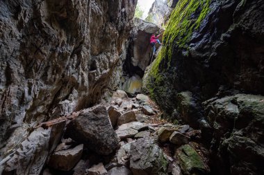 Maceracı kız kayalık bir mağaraya iniyor. Skaha Bluffs İl Parkı, Penticton, British Columbia, Kanada.
