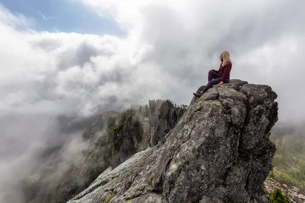 Bulutlu bir yaz sabahı engebeli kayalık dağın tepesinde Maceracı Kız. Crown Mountain'da çekilmiş, Kuzey Vancouver, Bc, Kanada.