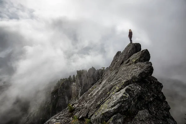 Bulutlu bir yaz sabahı engebeli kayalık dağın tepesinde Maceracı Kız. Crown Mountain'da çekilmiş, Kuzey Vancouver, Bc, Kanada.