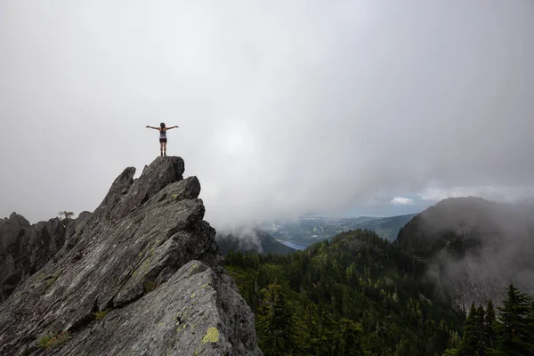 Bulutlu bir yaz sabahı engebeli kayalık dağın tepesinde Maceracı Kız. Crown Mountain'da çekilmiş, Kuzey Vancouver, Bc, Kanada.
