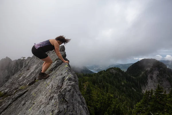 Bulutlu bir yaz sabahı engebeli kayalık dağın tepesinde Maceracı Kız. Crown Mountain'da çekilmiş, Kuzey Vancouver, Bc, Kanada.