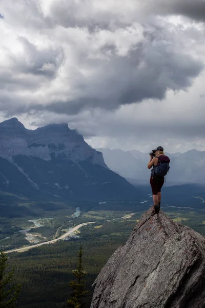 Maceracı Kız bulutlu ve yağmurlu bir gün boyunca kayalık bir dağın tepesinde fotoğraf çekmek. Lady Macdonald, Canmore, Alberta, Kanada'dan alındı.