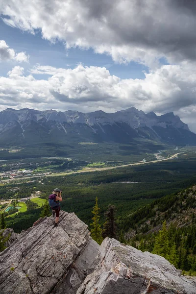 Maceracı Kız bulutlu ve yağmurlu bir gün boyunca kayalık bir dağın tepesinde fotoğraf çekmek. Lady Macdonald, Canmore, Alberta, Kanada'dan alındı.