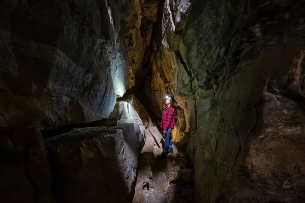 Maceracı kız Skaha Bluffs Provincial Park, Penticton, British Columbia, Kanada doğal bir mağaranın içinde keşfediyor.
