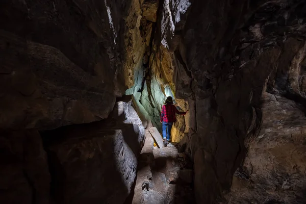 Maceracı kız Skaha Bluffs Provincial Park, Penticton, British Columbia, Kanada doğal bir mağaranın içinde keşfediyor.