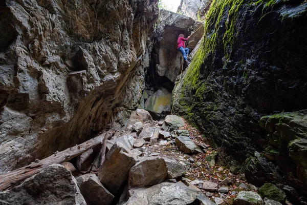Maceracı kız kayalık bir mağaraya iniyor. Skaha Bluffs İl Parkı, Penticton, British Columbia, Kanada.