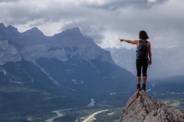 Maceracı Kafkas Kız bulutlu ve yağmurlu bir gün boyunca kayalık bir dağın üstüne bir parmak işaret. Lady Macdonald, Canmore, Alberta, Kanada'dan alındı.