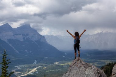 Açık kollu maceracı Kafkas Kız bulutlu ve yağmurlu bir gün boyunca kayalık dağın tepesinde. Lady Macdonald, Canmore, Alberta, Kanada'dan alındı.