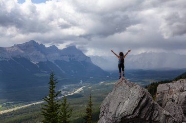 Açık kollu maceracı Kafkas Kız bulutlu ve yağmurlu bir gün boyunca kayalık dağın tepesinde. Lady Macdonald, Canmore, Alberta, Kanada'dan alındı.