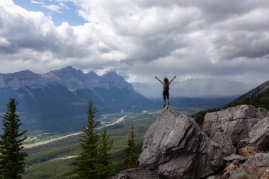 Açık kollu maceracı Kafkas Kız bulutlu ve yağmurlu bir gün boyunca kayalık dağın tepesinde. Lady Macdonald, Canmore, Alberta, Kanada'dan alındı.