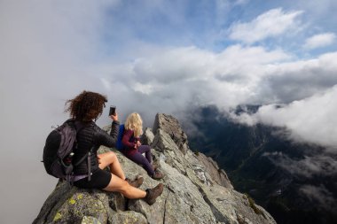 Bulutlu bir yaz sabahı engebeli kayalık dağın tepesinde Maceracı Kız. Crown Mountain'da çekilmiş, Kuzey Vancouver, Bc, Kanada.