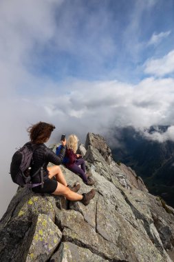 Bulutlu bir yaz sabahı engebeli kayalık dağın tepesinde Maceracı Kız. Crown Mountain'da çekilmiş, Kuzey Vancouver, Bc, Kanada.