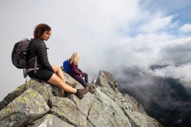 Bulutlu bir yaz sabahı engebeli kayalık dağın tepesinde Maceracı Kız. Crown Mountain'da çekilmiş, Kuzey Vancouver, Bc, Kanada.