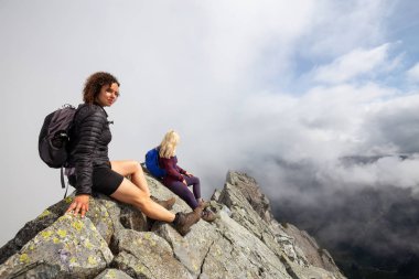 Bulutlu bir yaz sabahı engebeli kayalık dağın tepesinde Maceracı Kız. Crown Mountain'da çekilmiş, Kuzey Vancouver, Bc, Kanada.