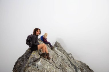 Bulutlu bir yaz sabahı engebeli kayalık dağın tepesinde Maceracı Kız. Crown Mountain'da çekilmiş, Kuzey Vancouver, Bc, Kanada.