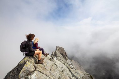 Bulutlu bir yaz sabahı engebeli kayalık dağın tepesinde Maceracı Kız. Crown Mountain'da çekilmiş, Kuzey Vancouver, Bc, Kanada.