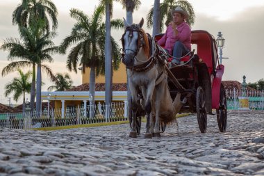 Trinidad, Küba - 12 Haziran 2019: Canlı ve renkli bir gün batımı nda küçük bir Küba Kasabasının sokaklarında At Arabası.