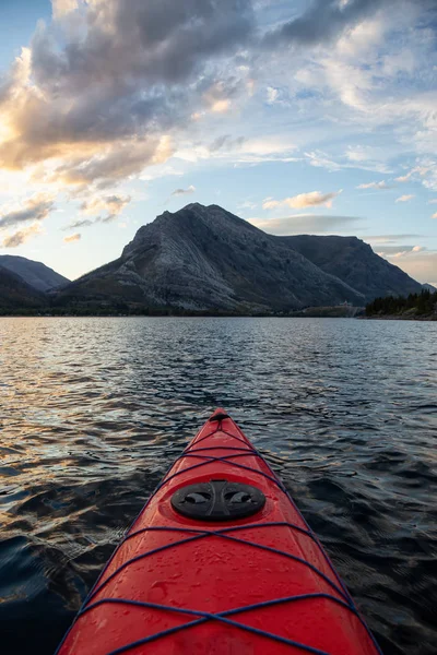 Buzul Gölü 'nde kayak yaparken bulutlu bir yaz günbatımında güzel Kanada Rocky Dağları etrafını sarmıştı. Yukarı Waterton Gölü, Alberta, Kanada.