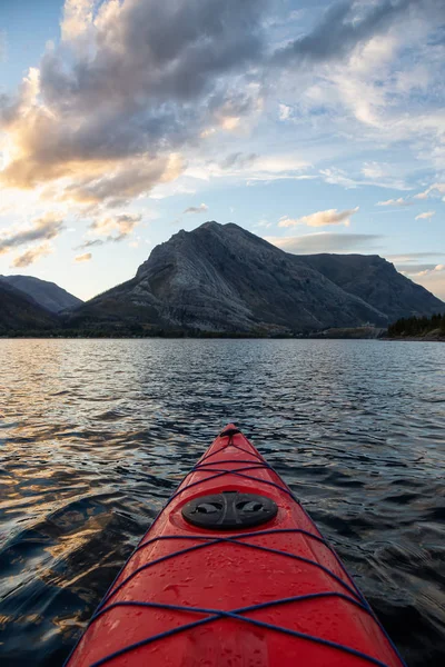 Buzul Gölü 'nde kayak yaparken bulutlu bir yaz günbatımında güzel Kanada Rocky Dağları etrafını sarmıştı. Yukarı Waterton Gölü, Alberta, Kanada.