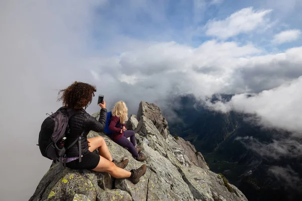 Bulutlu bir yaz sabahı engebeli kayalık dağın tepesinde Maceracı Kız. Crown Mountain'da çekilmiş, Kuzey Vancouver, Bc, Kanada.