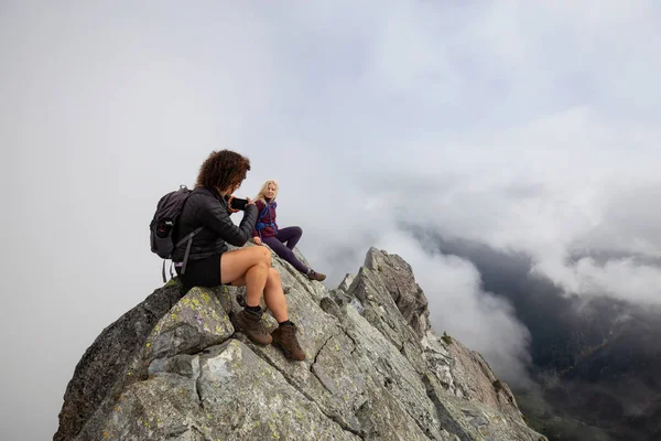 Bulutlu bir yaz sabahı engebeli kayalık dağın tepesinde Maceracı Kız. Crown Mountain'da çekilmiş, Kuzey Vancouver, Bc, Kanada.
