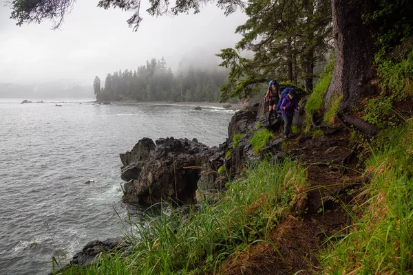 Maceracı arkadaşlar sisli bir yaz günü boyunca Pasifik Okyanusu Kıyısındaki Sombrio Plajı'na Juan de Fuca Trail yürüyüş vardır. Port Renfrew yakınlarında çekilen Vancouver Adası, Bc, Kanada.