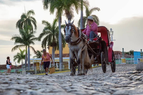 Trinidad, Küba - 12 Haziran 2019: Canlı ve renkli bir gün batımı nda küçük bir Küba Kasabasının sokaklarında At Arabası.